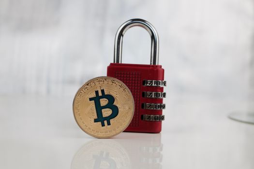 Cryptocurrency physical gold bitcoin coin and red numeric padlock.