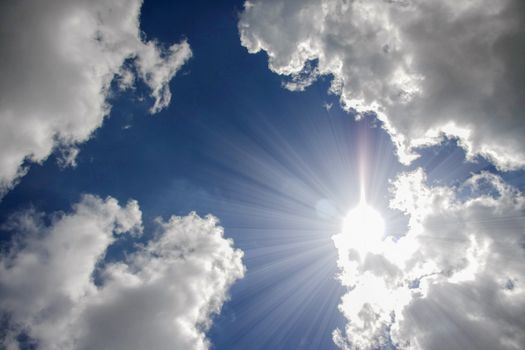 sunlight reflex above white clouds and blue sky on background