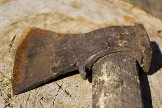 Old rusty ax against the background of a wooden stump