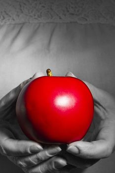 Red ripe apple in hands on a background of dress with lace