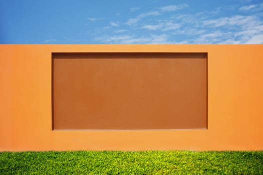 beautiful orange wall, modern cement fence with grass field and blue sky on bright day