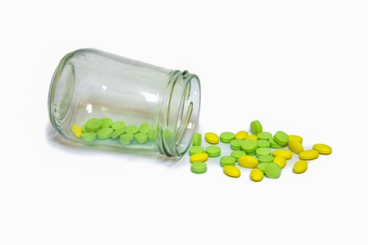 green and yellow pills medicine was pouring from glass bottle