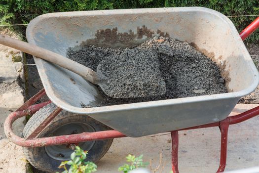 Wheelbarrow on a construction site filled with concrete.