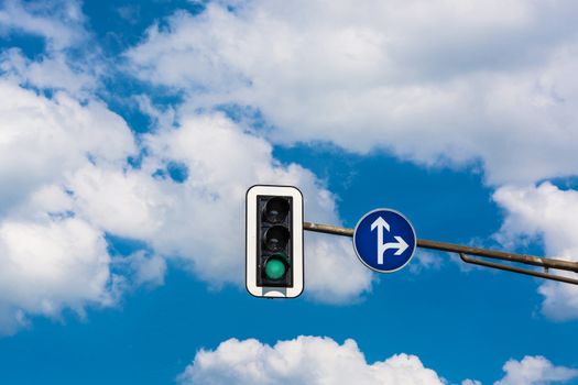 A traffic light and a surveillance camera on a pole mounted on the street.