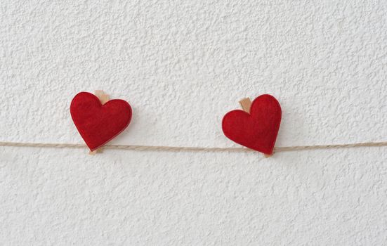 Two hearts with clothes pegs on a cord on structure plaster