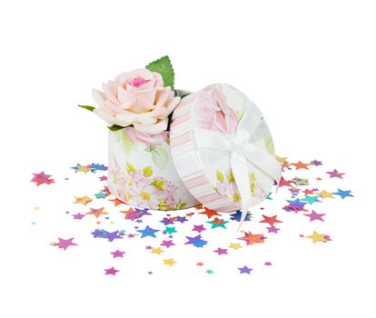 Round gift box with rose flower on a background of confetti in the form of stars,  isolated on white