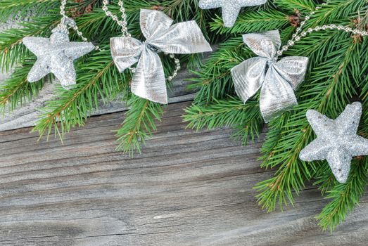 Christmas composition with fir branches and silver decorations on old boards; with copy-space