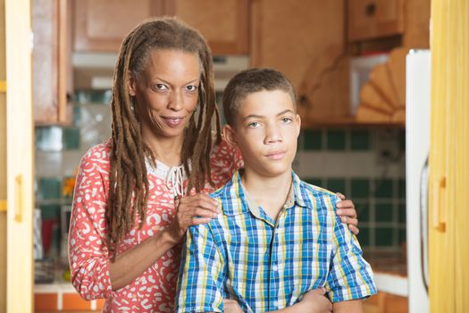 African-American mother and her frustrated teenaged son stand together in kitchen