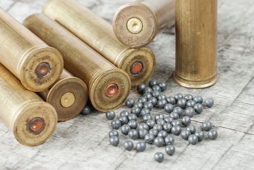 Metal sleeves for hunting rifle and large lead shot on a wooden background