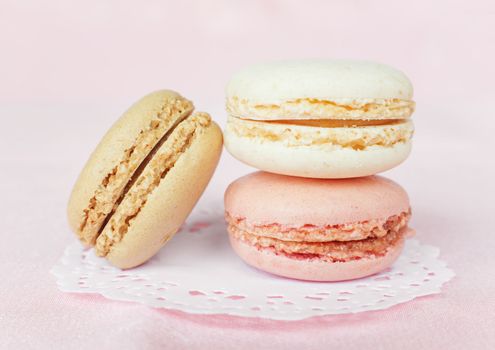 Several multicolored macaroons pastel colors on pink background