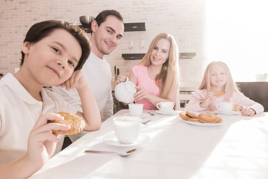 Happy family with children having breakfast at home