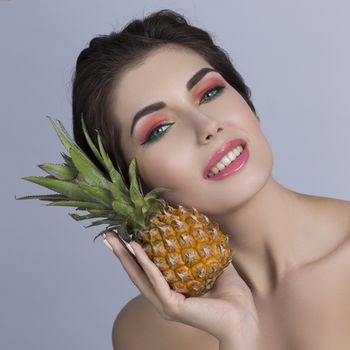 Portrait of a beautiful woman with perfect skin holding pineapple, isolated on white background