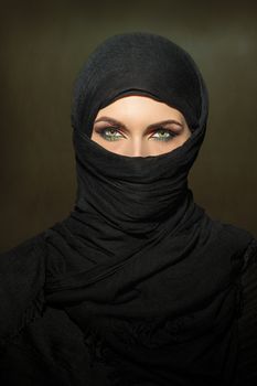 Beautiful muslim woman in niqab traditional veil against on dark background