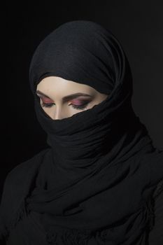 Beautiful muslim woman in niqab traditional veil against on dark background