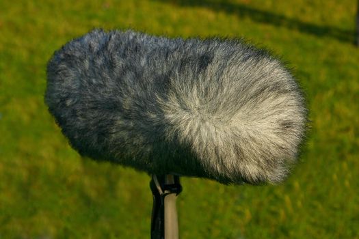 A large boom microphone on a grass background