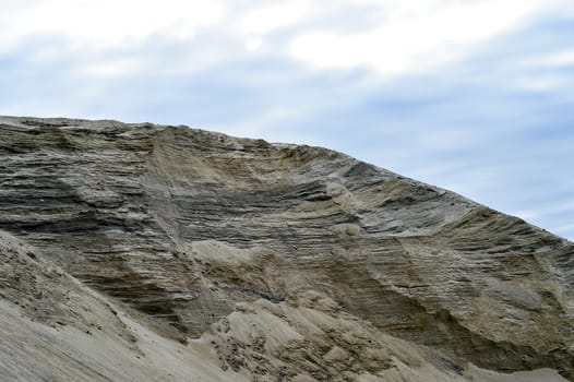 Sandy hill in a quarry against the sky.
