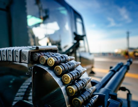 Large caliber bullets in belt up close. Defocused background of helicopter and associated gun. Imagery for weapons, military and war.