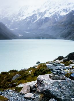 Rocks piled in a cairn in front of hooker lake in New Zealand. Tranquil scene with mountains in the background.