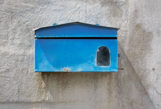 blue mailbox front of old cement wall of home