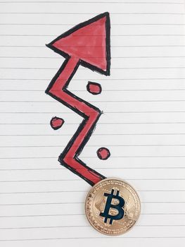 Cryptocurrency physical gold bitcoin coin and red arrow