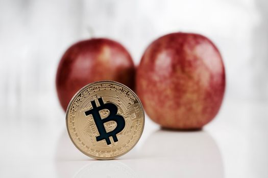 Digital currency physical gold bitcoin coin near apple.