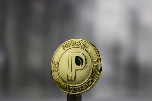 Cryptocurrency physical gold peercoin coin with a green leaf.