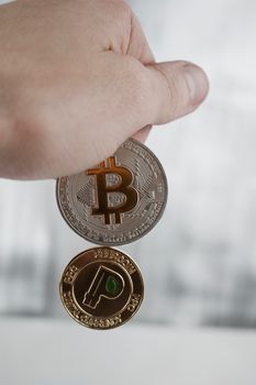 Cryptocurrency physical silver bitcoin and gold peercoin in hand.