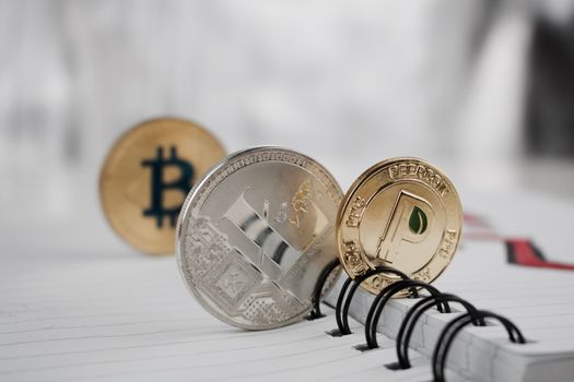 Digital currency physical peercoin, bitcoin and litecoin in notebook.