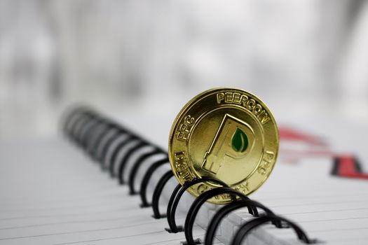 Digital currency physical gold peercoin coin in notebook.