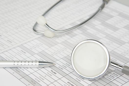 Old silver stethoscope and pen place on finance account with white background.