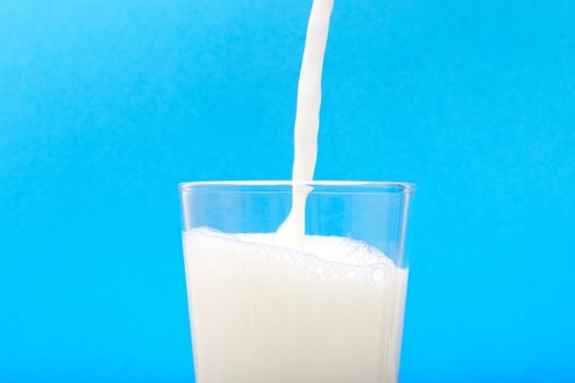 Milk when inflowing into the jar with blue background