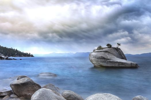 This is an image of Lake Tahoe during a summer storm. The large rock in the lake is a called Bonzai Rock.