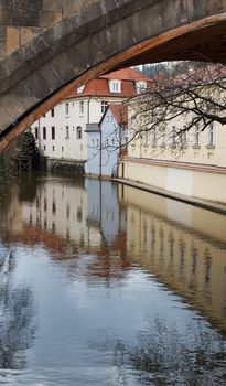Building reflection in water under bridge in Prague