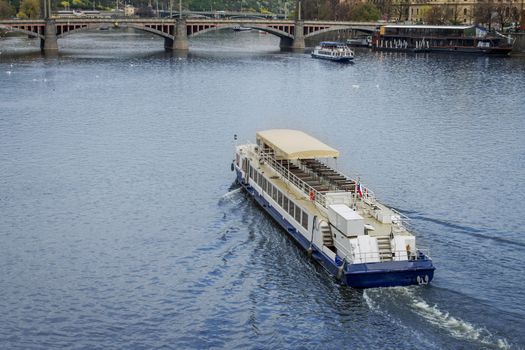Boat on Vltava river going under bridge in Prague