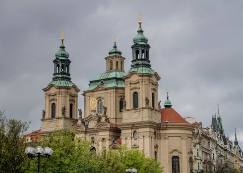 The Church of St. Nicholas behind the trees in Prague, dramatic sky