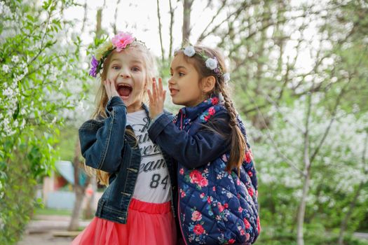 Two girls sharing shocked news among spring garden