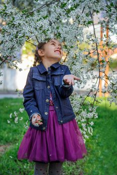 Happy girl enjoying flying petals among garden