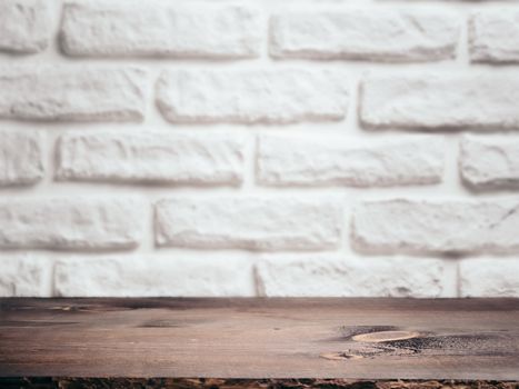 Empty wooden table over white brick wall as background. Brown wooden background for mock up, product montage display.