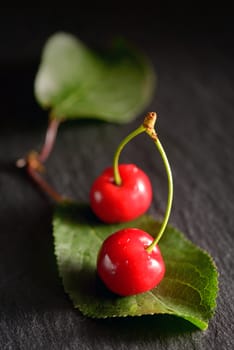 cherries with leaf on black ardesia  plate
