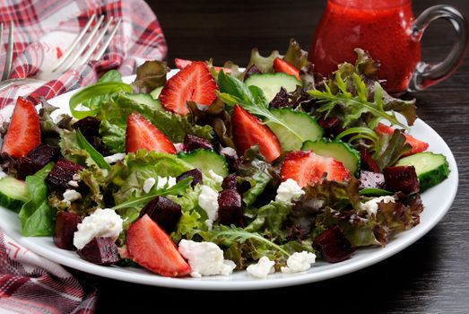 Salad of vinaigrette with strawberries, tender feta and strawberry sauce. Horizontal shot. Foreground close-up.