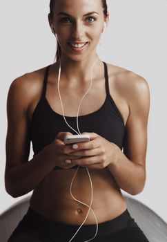 Shot of a beautiful young woman setting the music playlist for the workout.