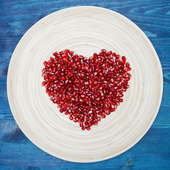 peeled pomegranate seeds on a plate in the form of heart