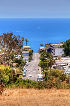 High hillside view of a Laguna Beach street that leads down to the ocean in Summer.