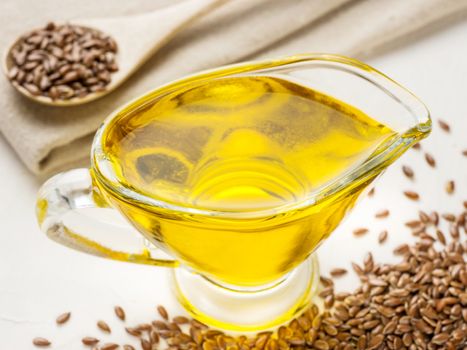 Brown flax seeds and flaxseed oil in glass jug on trendy textured white concrete background. Flax oil is rich in omega-3 fatty acid.