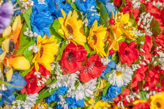 a lot of homemade artificial colored flowers in a beautiful sunny day