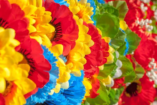 a lot of homemade artificial colored flowers in a beautiful sunny day