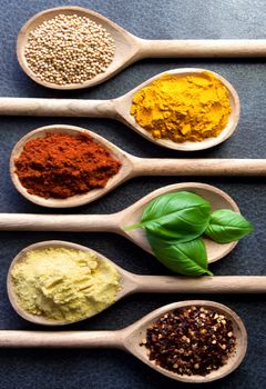 Closeup of assorted herbs and spices in wooden spoons 