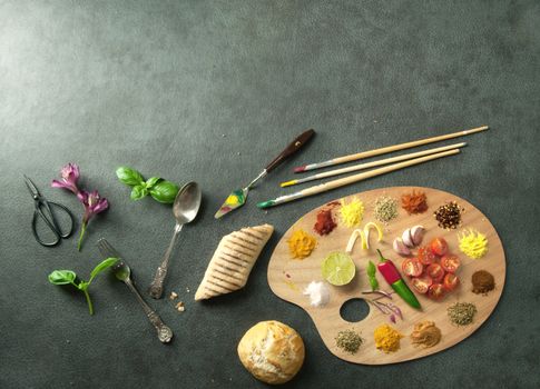 Fresh cooking ingredients including herb and spices on a painters palette with space
