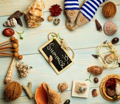 Summer Vacations Concept with Various Shells, Dry Plants, Handmade Decorations and Chalk Board with Inscription Summer closeup on Light Blue Wooden background. Retro Styled
