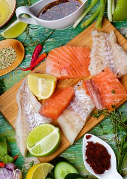 Food Background of Raw Thai Fish Cakes Ingredients with Vegetables, Spices, Herbs, Fruits, Prawns and Delicious Fillet of Salmon and Cod closeup on Cracked Wooden background